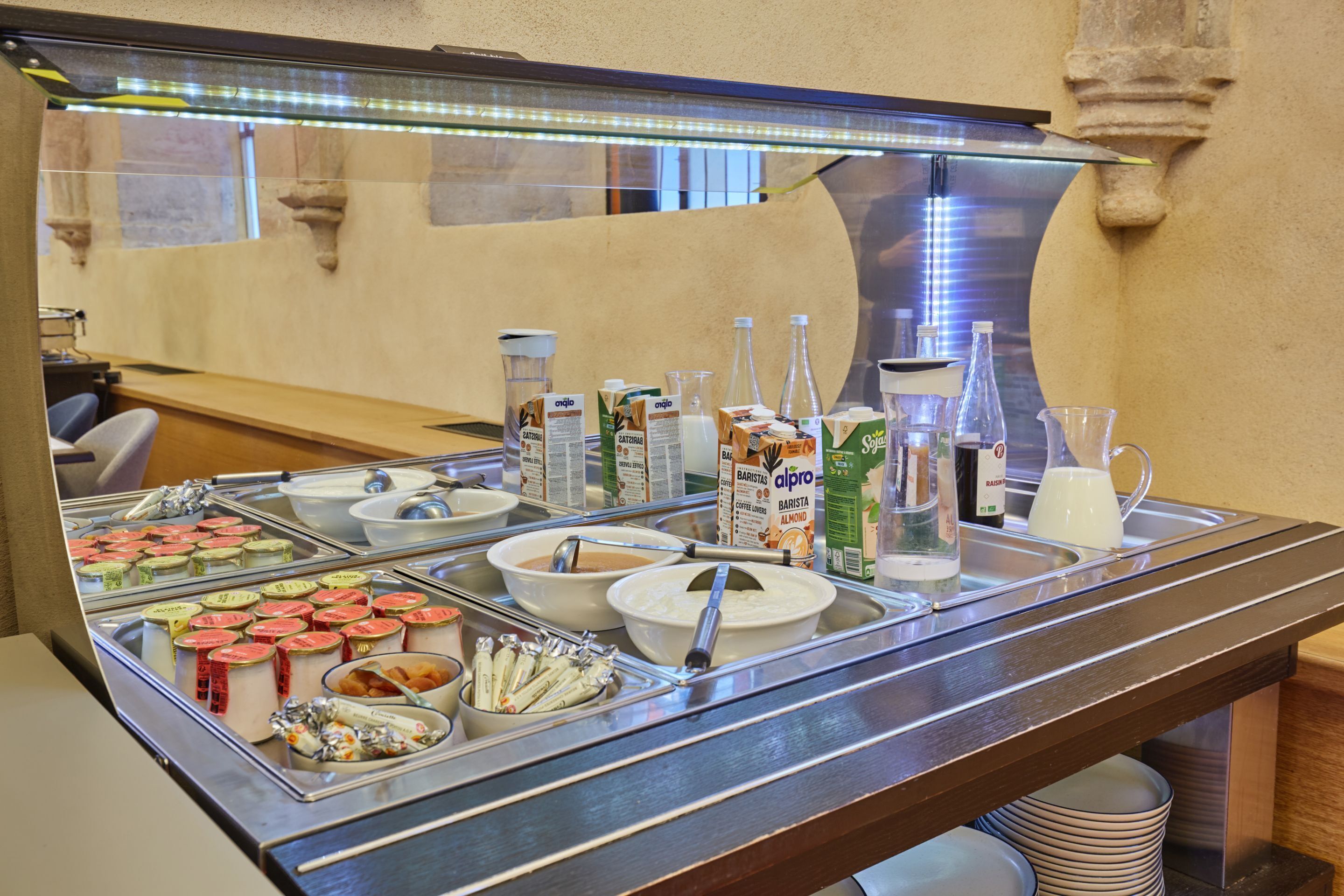 A buffet with various food items and beverages, including yogurt, cereal, and milk.