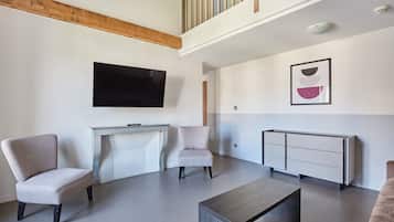 Een moderne woonkamer met een hoge plafond, een open haard, een flatscreen televisie en een minimalistische indeling.