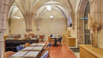 A dining area with tables and chairs, stone arches, and a reception desk.