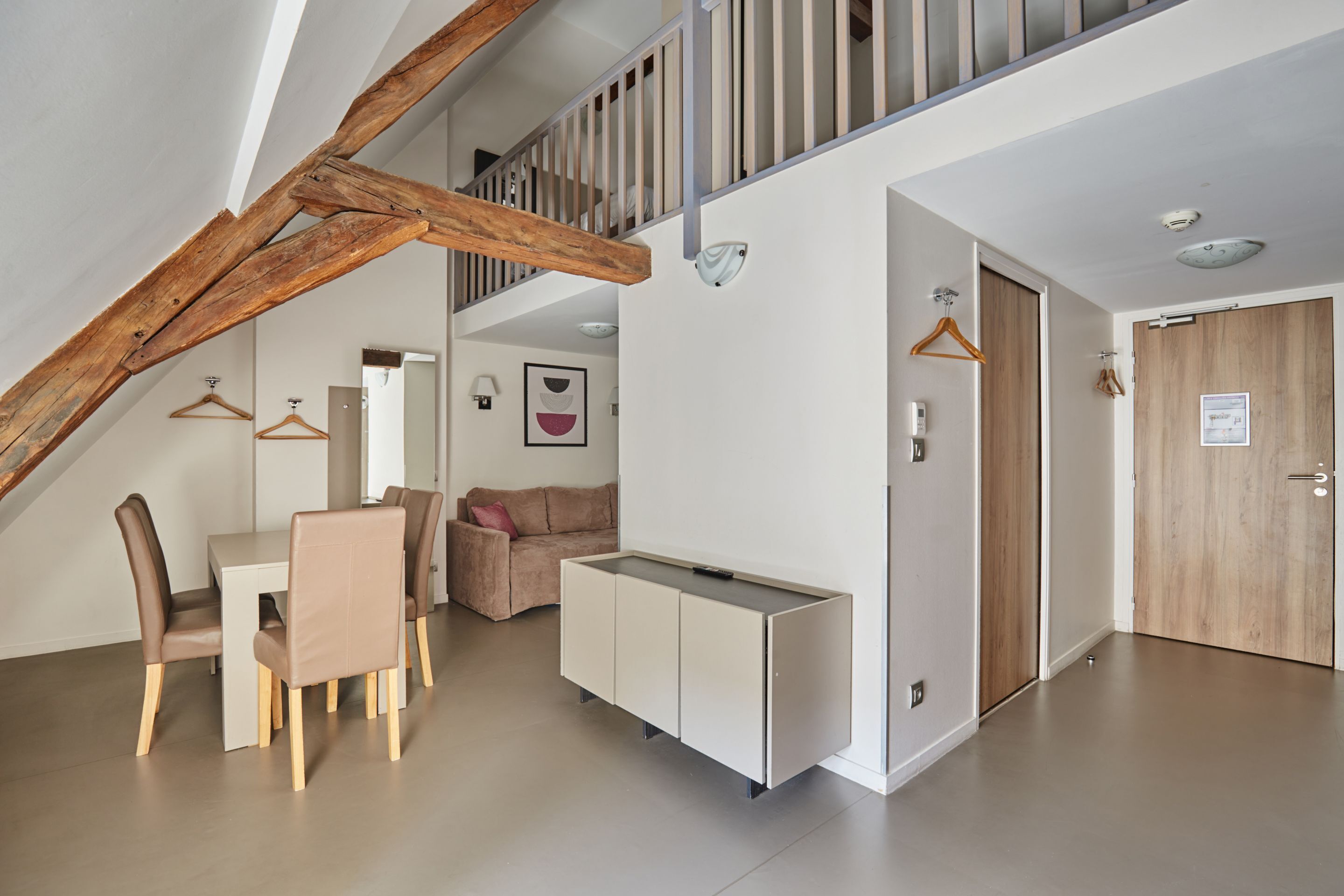 A modern interior with a dining area, a sofa, a cabinet, and a staircase.
