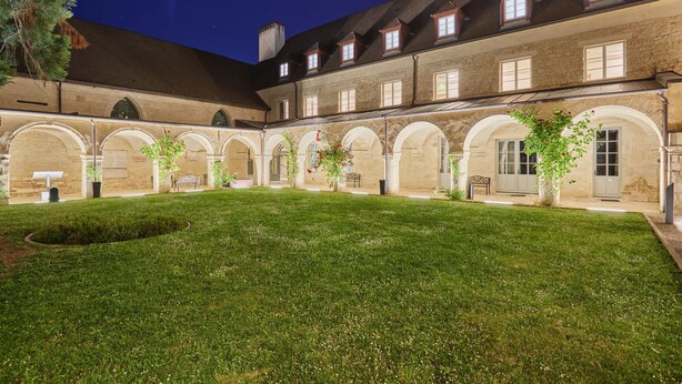 A courtyard with a lawn, stone walls, and arched walkways. - Appart'hôtel Odalys City - Dijon Centre Les Cordeliers (Dijon)