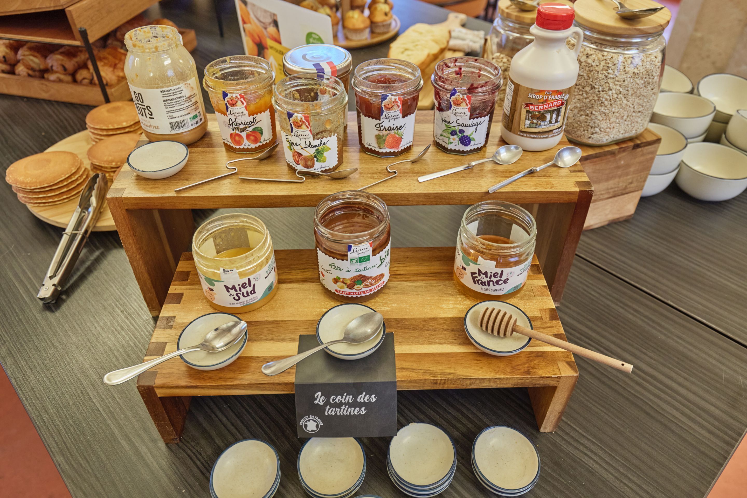 A display of various food items including jars of honey, jams, and sauces, with spoons and bowls for serving.