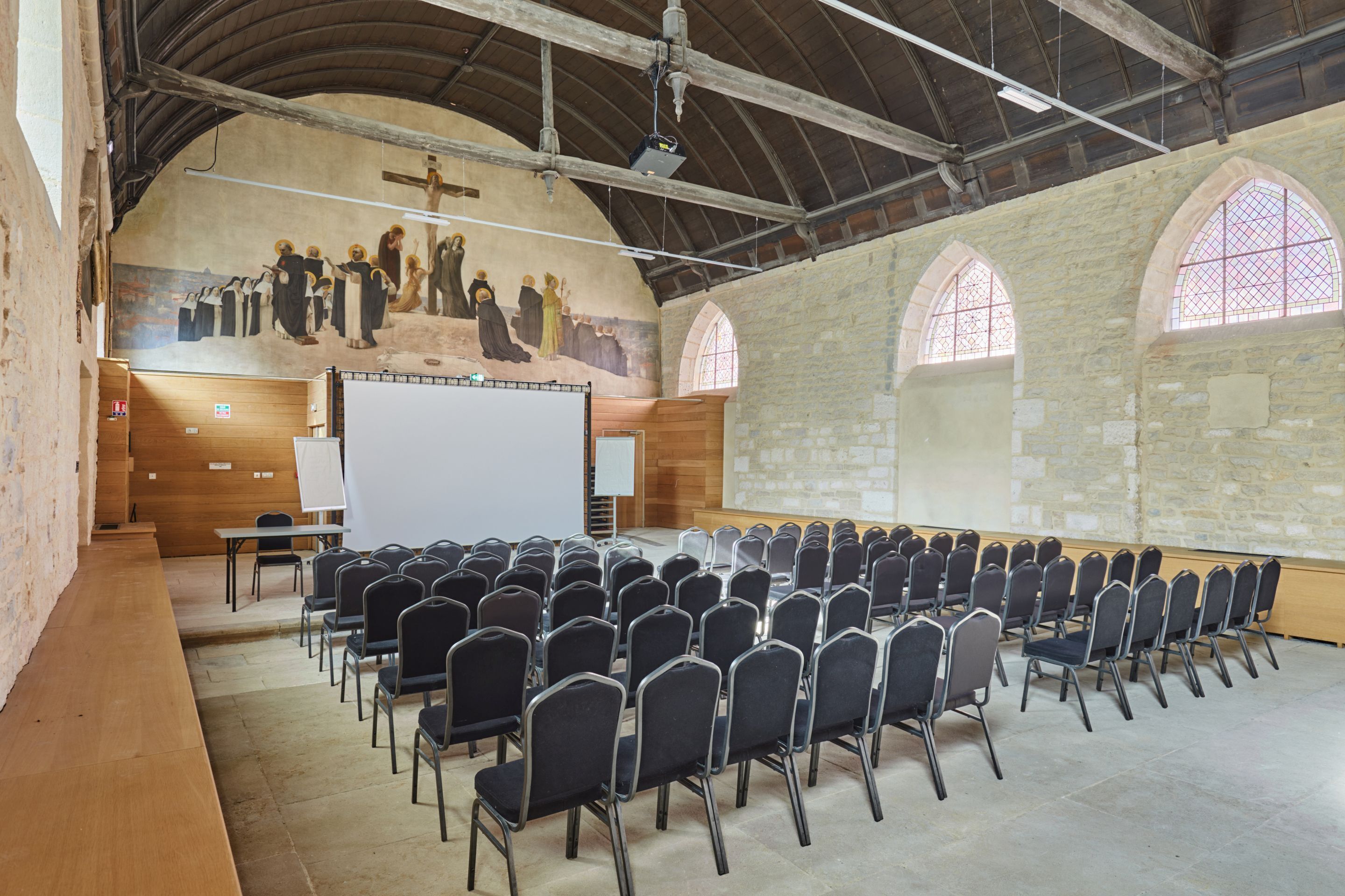 A church interior with rows of chairs, a whiteboard, and a mural on the wall.