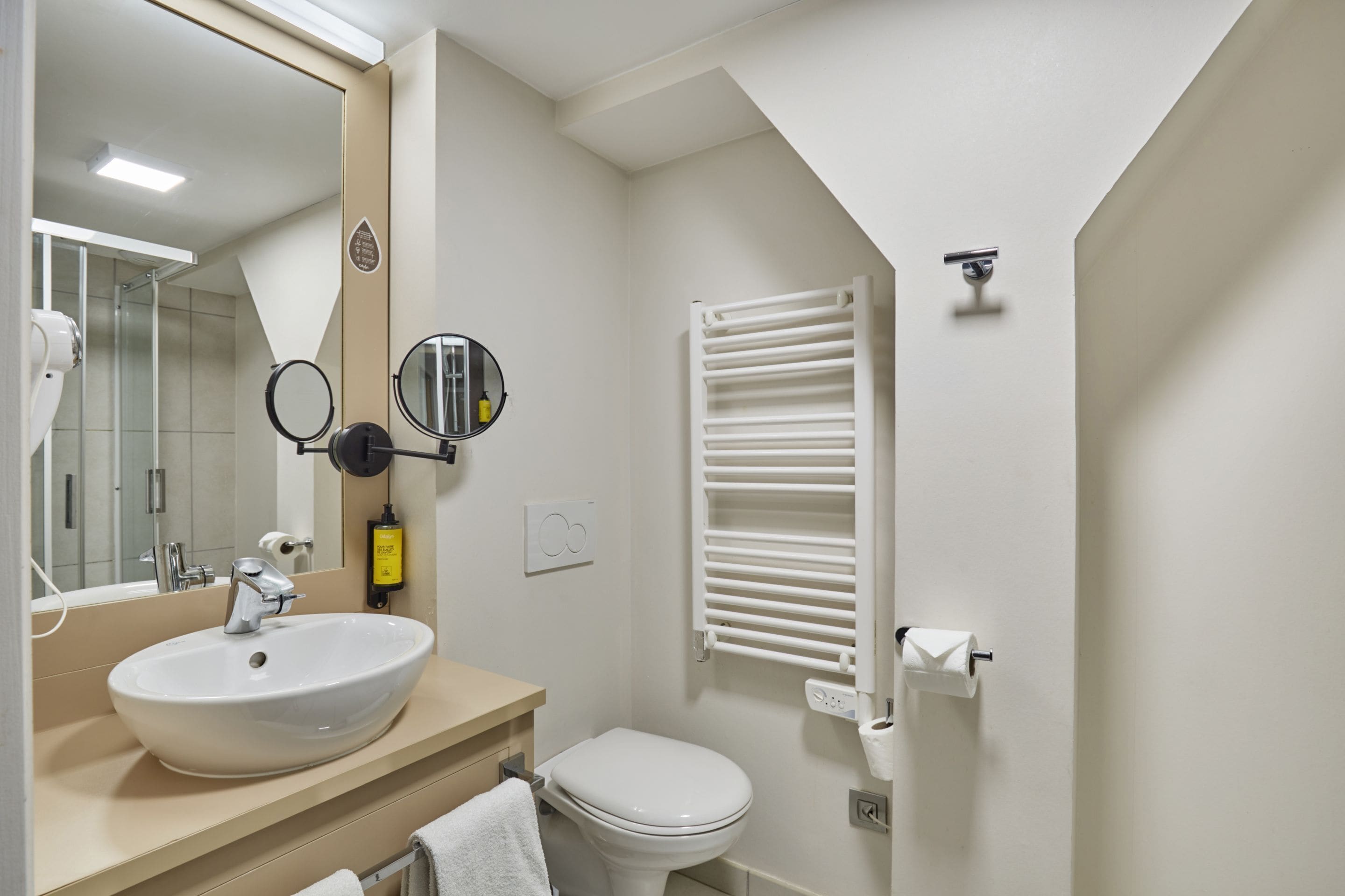 A modern bathroom with a sink, mirror, toilet, and towel rack.