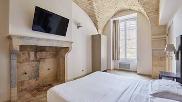 Een slaapkamer met een stenen openhaard, een flatscreentelevisie aan de wand en een groot bed.