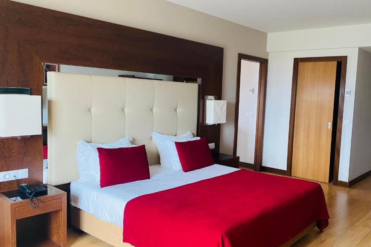 Habitación de hotel con una cama grande, una mesita de noche con teléfono, una mesita auxiliar de madera y un armario.