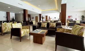 Un hall de hotel con zonas de estar, una recepción y una mesa de centro.