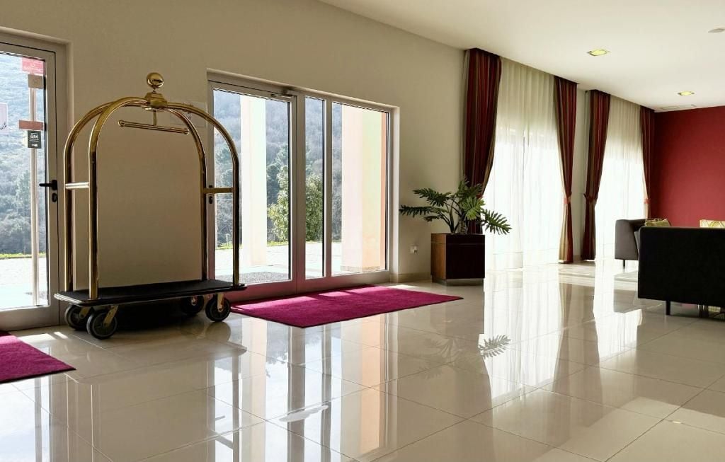 Un vestíbulo de hotel con un ventanal grande, una recepción y una planta.