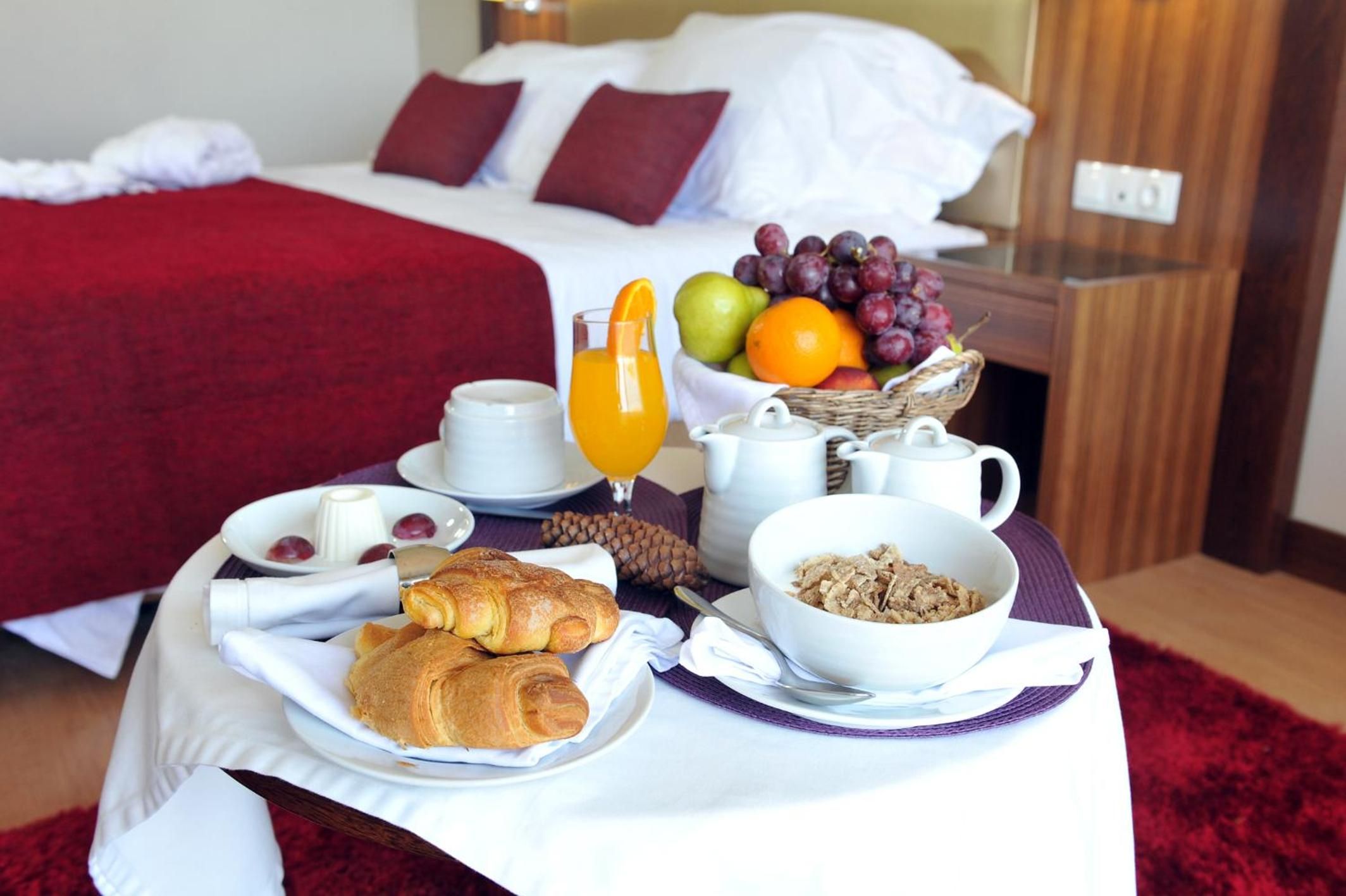 Desayuno con croissants, fruta y una jarra de jugo de naranja sobre una mesa en una habitación de hotel.