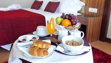 Desayuno con croissants, fruta y una jarra de jugo de naranja sobre una mesa en una habitación de hotel.