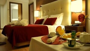 Habitación de hotel con una cama grande, una mesita de noche con productos de desayuno y una lámpara.