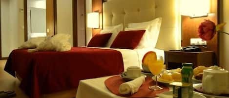A hotel room with a large bed, a bedside table with breakfast items, and a nightstand with a lamp.