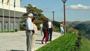 Un grupo de personas en un área pavimentada, con vista a un paisaje montañoso.