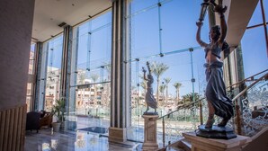 A spacious lobby with large windows, a statue, and a staircase. - Sunny Days El Palacio Resort & Spa - All inclusive (Hurghada)