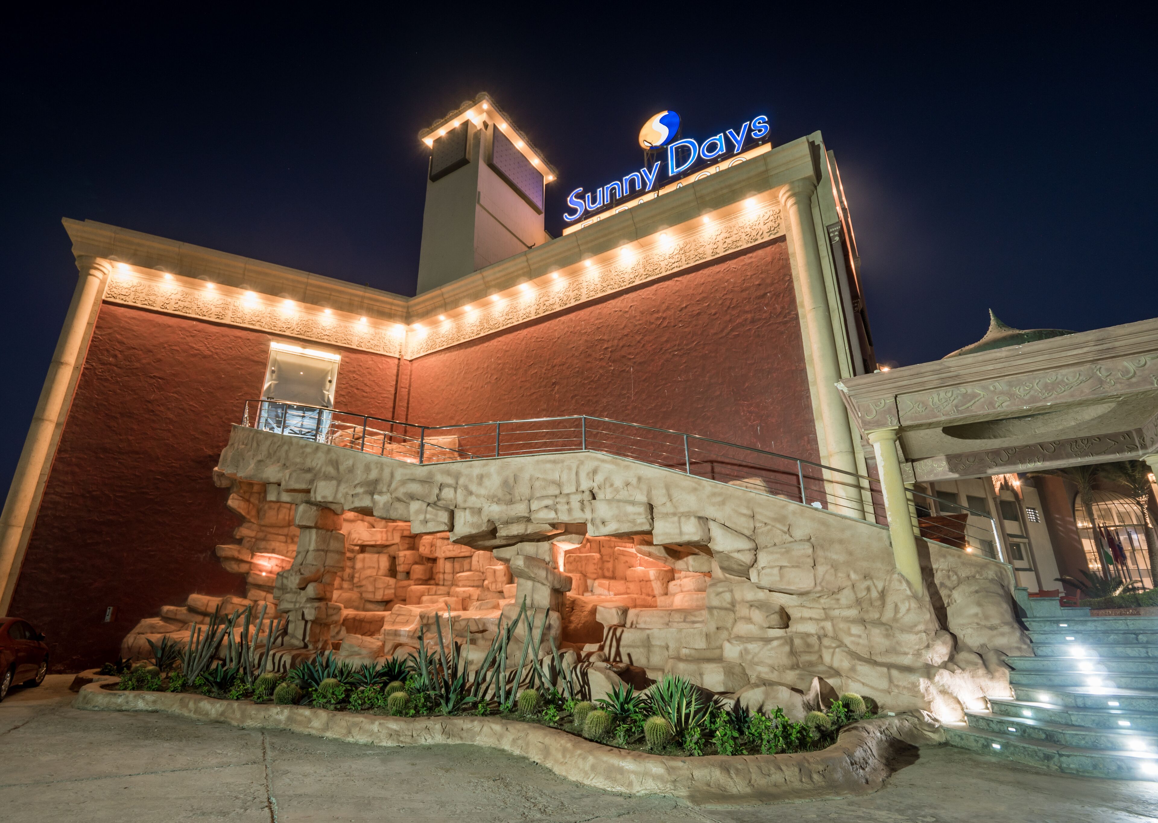 A building with a 'Sunny Days' sign, a stone facade, and a staircase leading to an upper level.