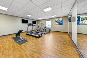 A gym with treadmills, elliptical machines, and a stationary bike, featuring wooden flooring and ceiling lights. - Comfort Inn & Suites West - Medical Center (Rochester)