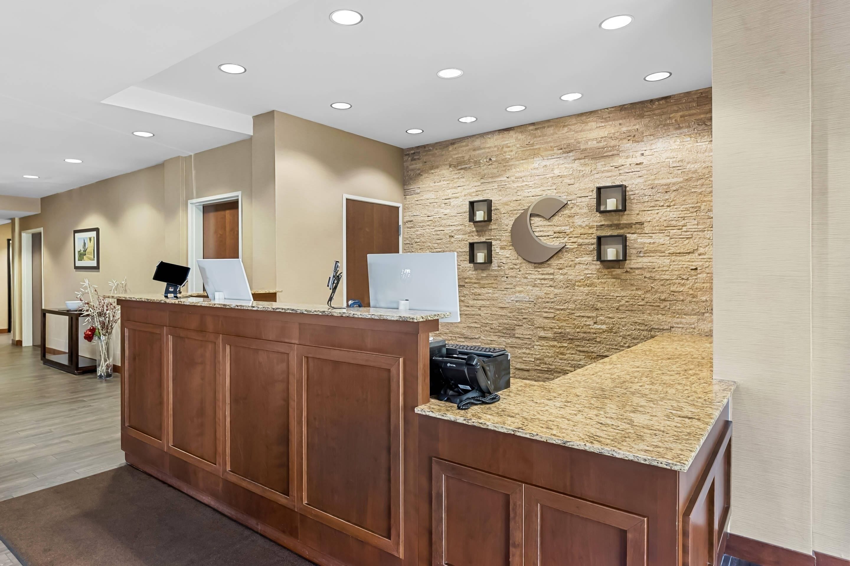 A reception area with a wooden counter, a stone wall, and a large C-shaped sign.