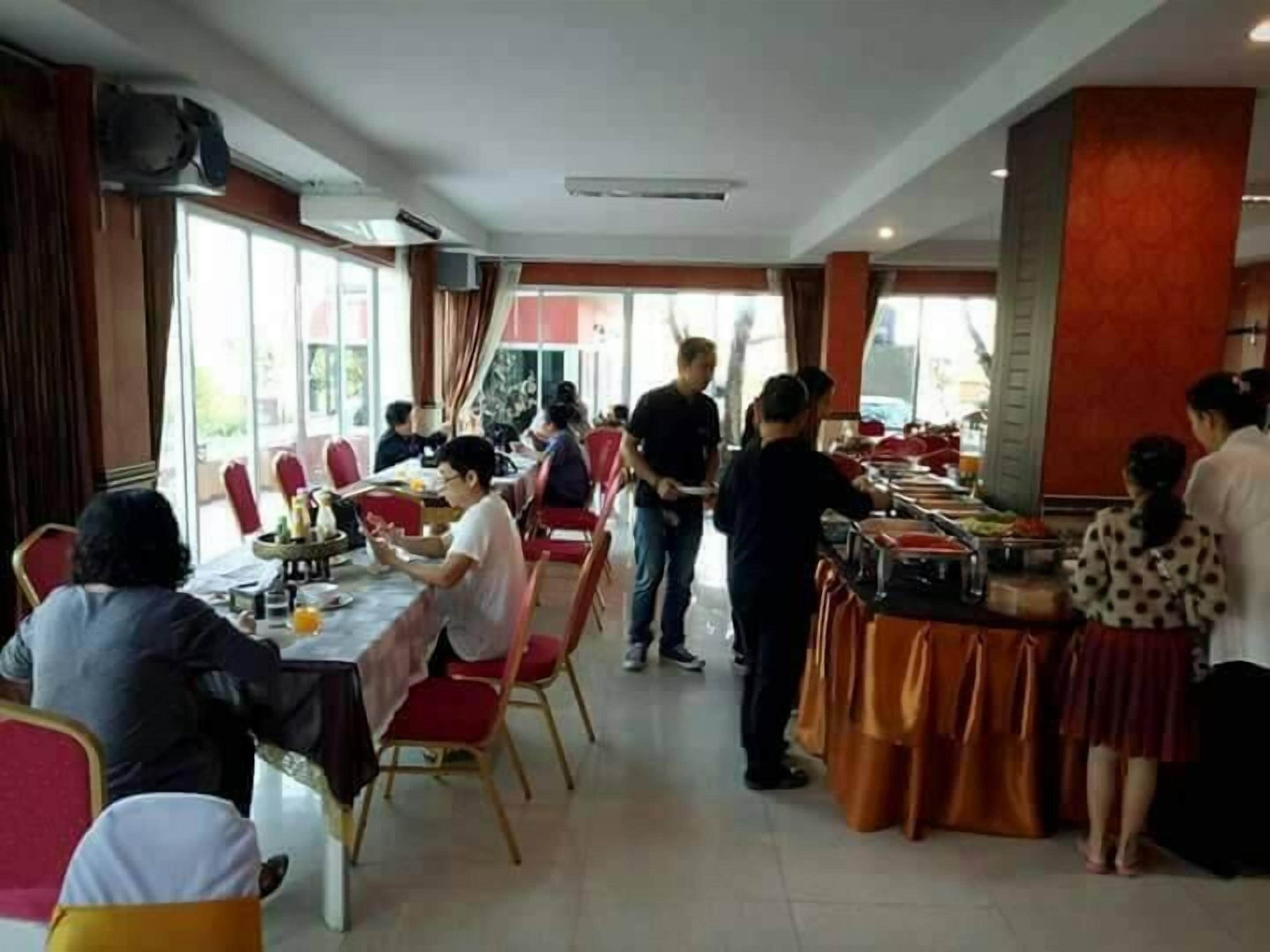 A dining area with tables and chairs, a buffet setup, and large windows.