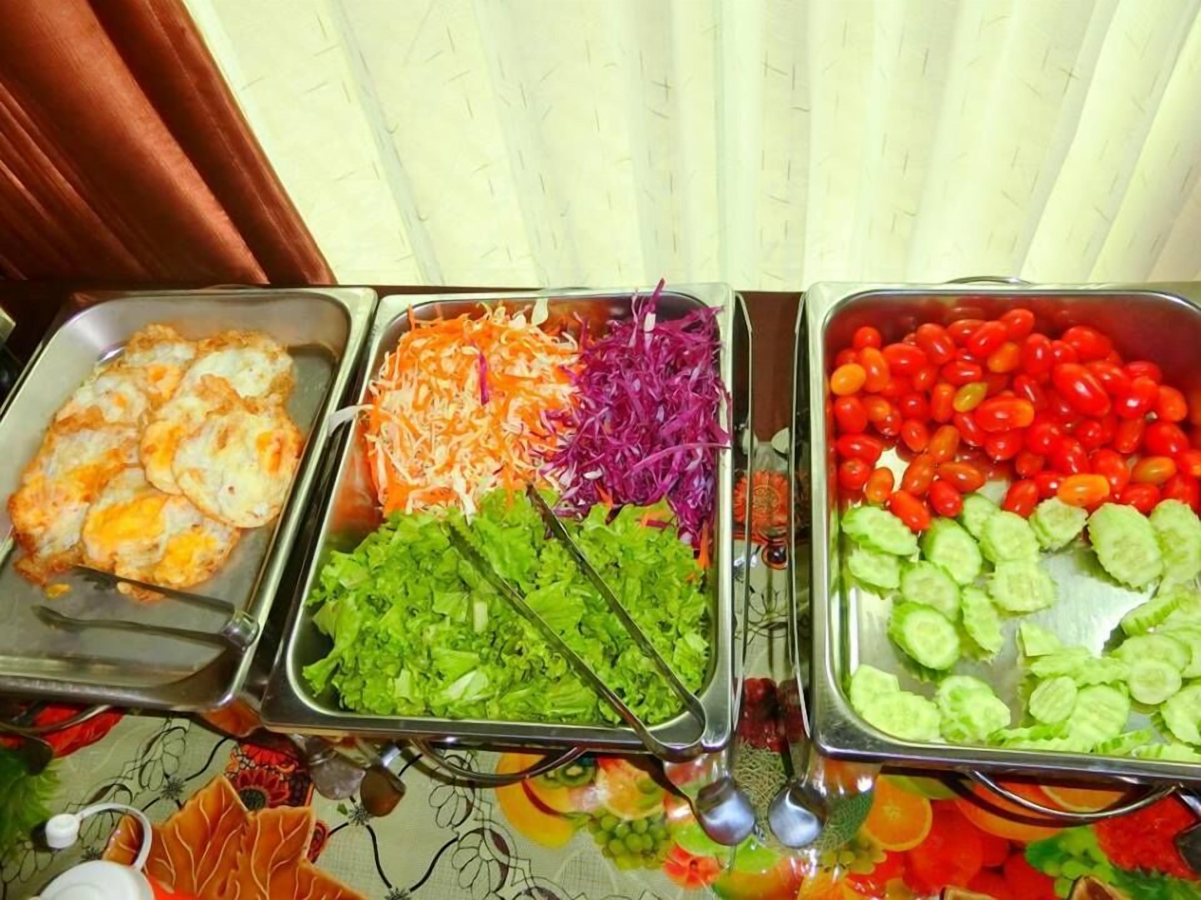 A buffet with various food items including fried eggs, shredded vegetables, and sliced cucumbers.