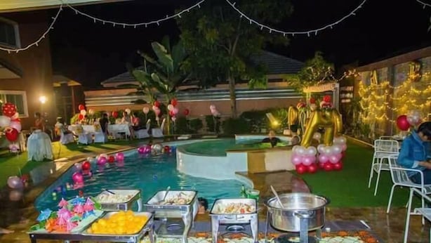 An outdoor pool area with food service stations, balloons, and string lights. - Le Parc Wangnang (Phitsanulok)