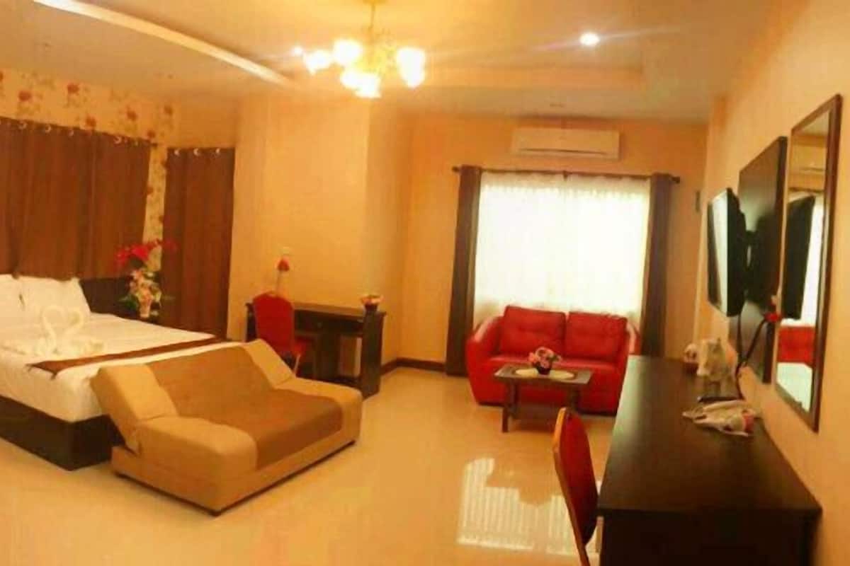 A hotel room with a bed, a sofa, a desk, and a mirror.