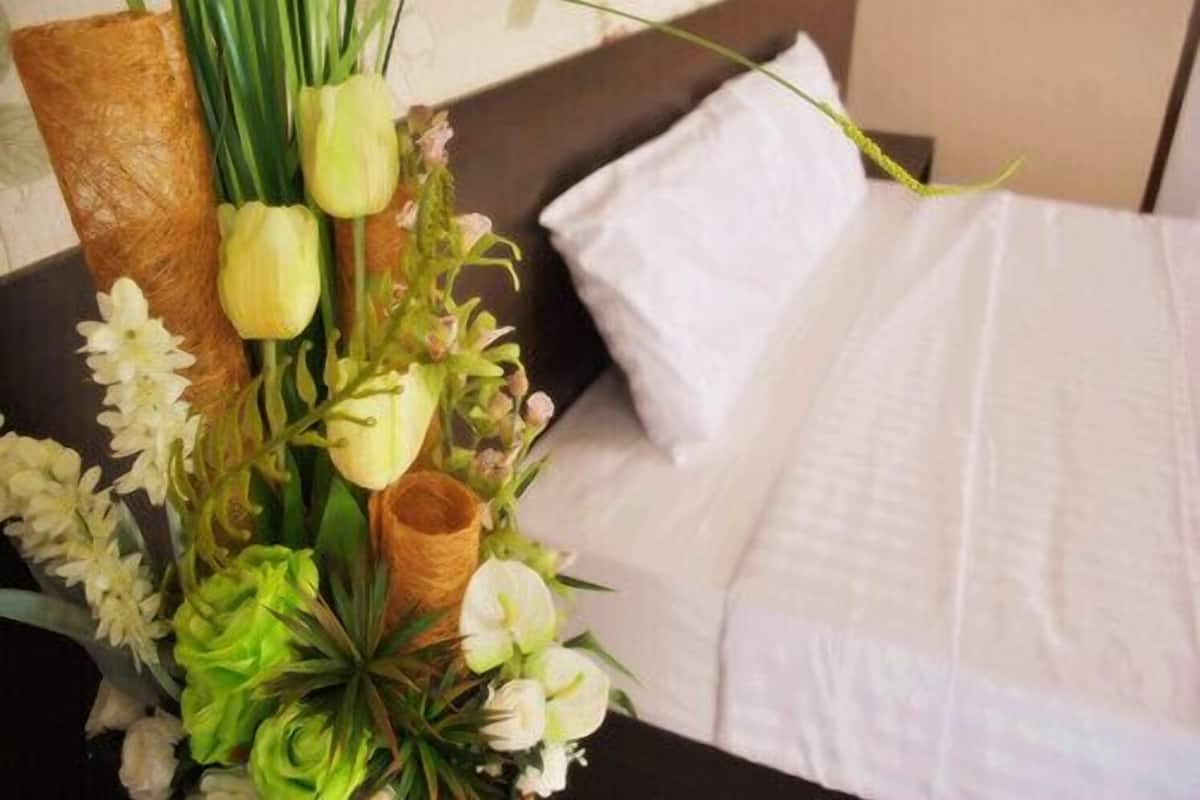 A bed with white linens and a floral arrangement on a bedside table.