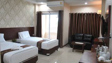 A hotel room with two beds, a sofa, a small table, and a TV.