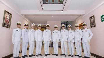 A group of uniformed personnel standing in a hallway with a ceiling light fixture and framed artwork on the walls.