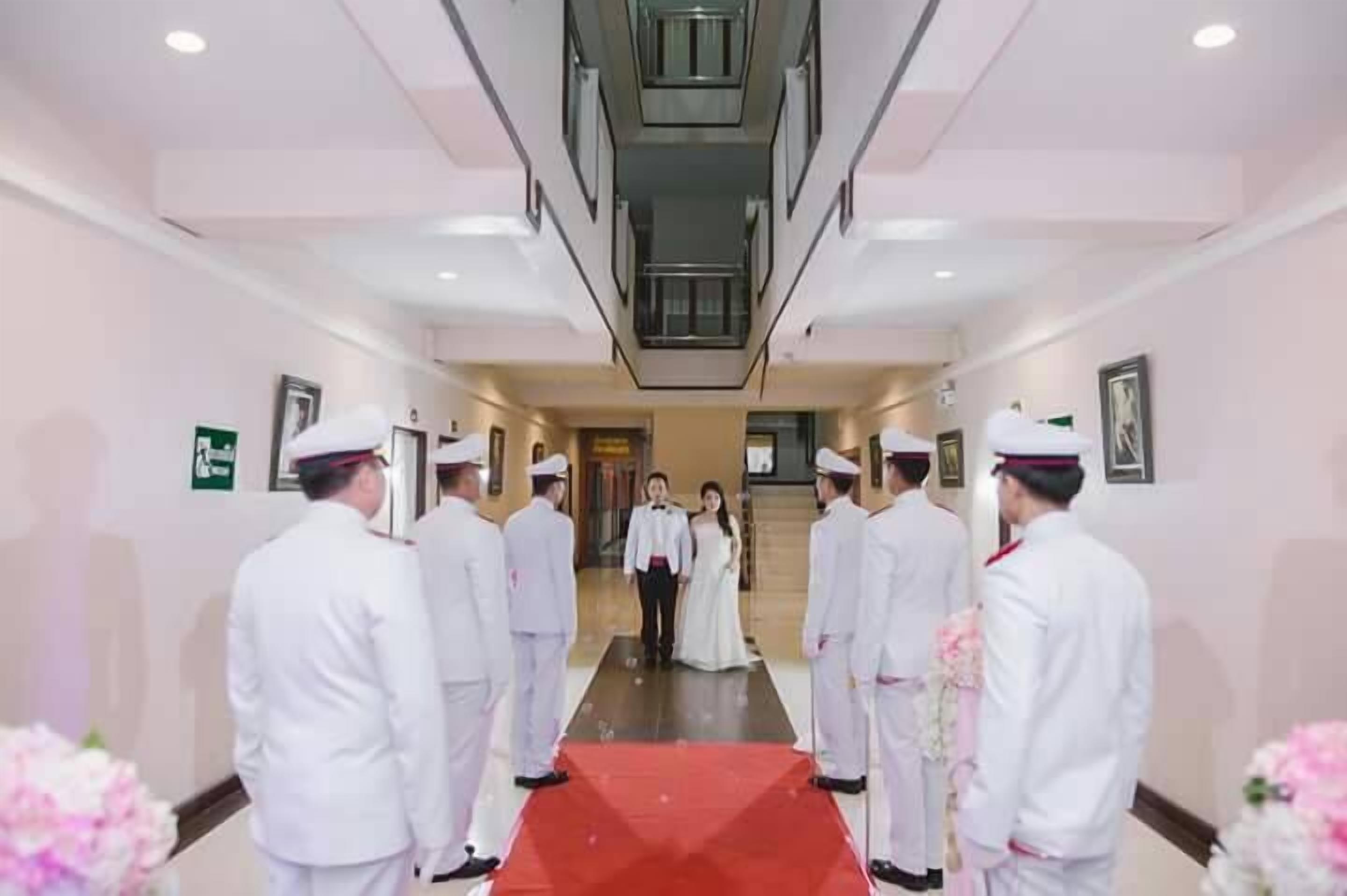 A ceremonial hallway with a red carpet leading to a couple at the end.