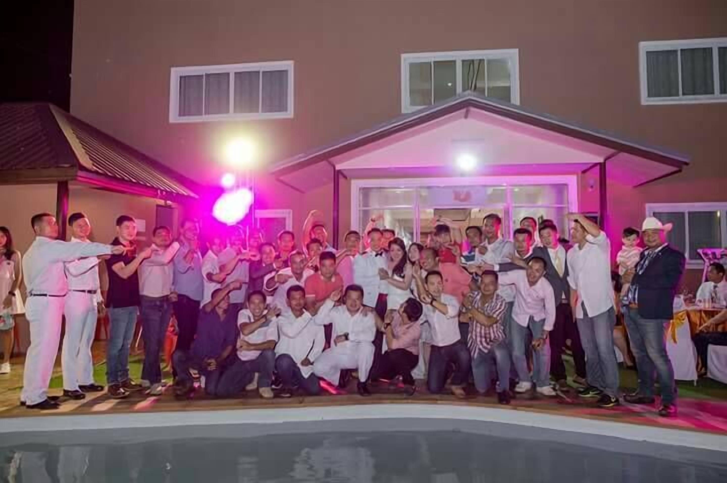 A group of people gathered outside a building with a pool.