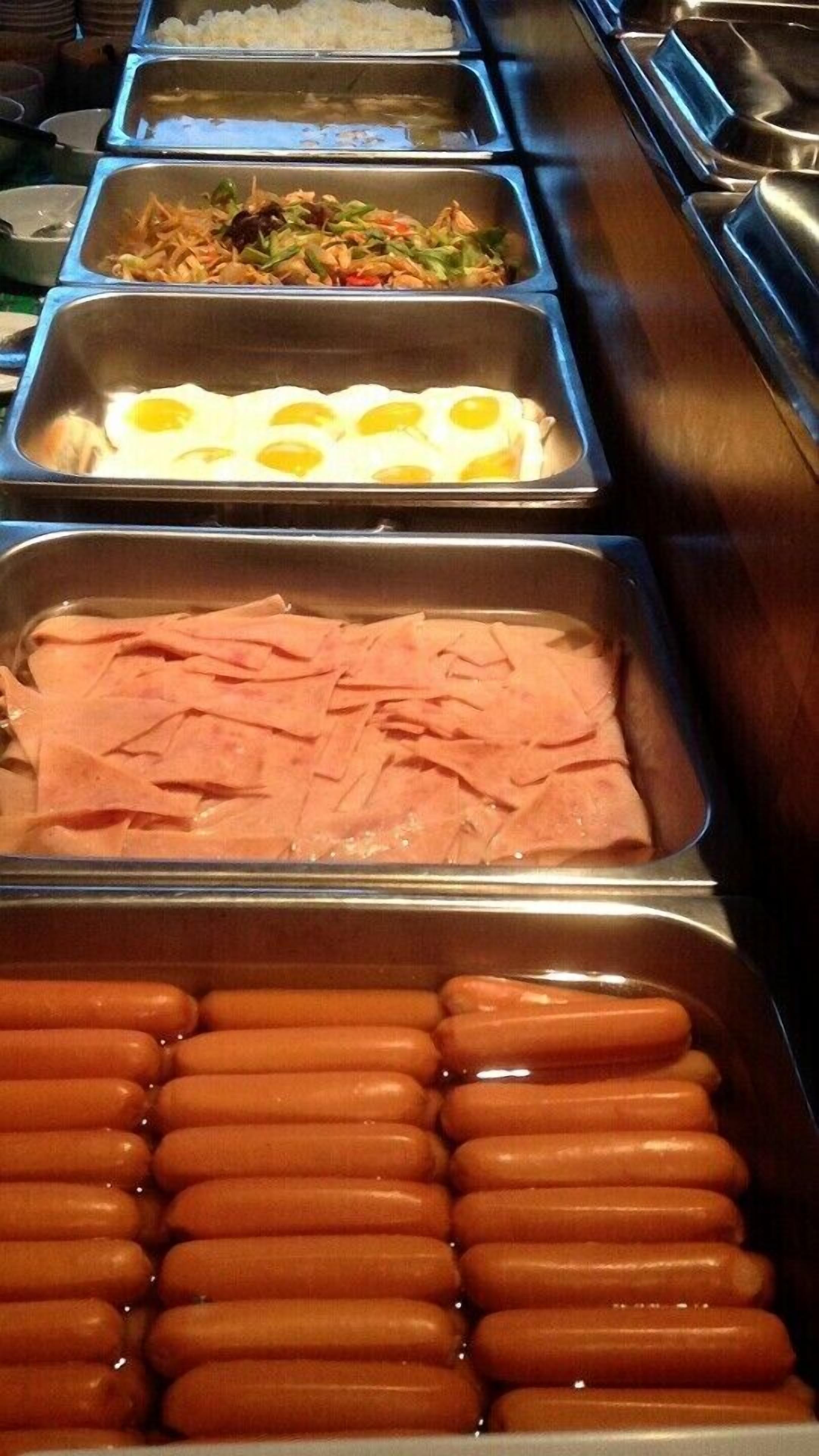 A buffet with various food options including eggs, ham, and sausages.