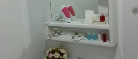 A bathroom with a white sink, mirror, and shelves with toiletries.
