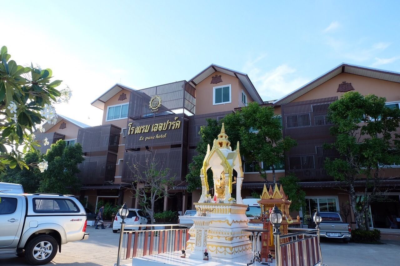 A building with a sign reading "Le parc hotel" and a golden statue in front.