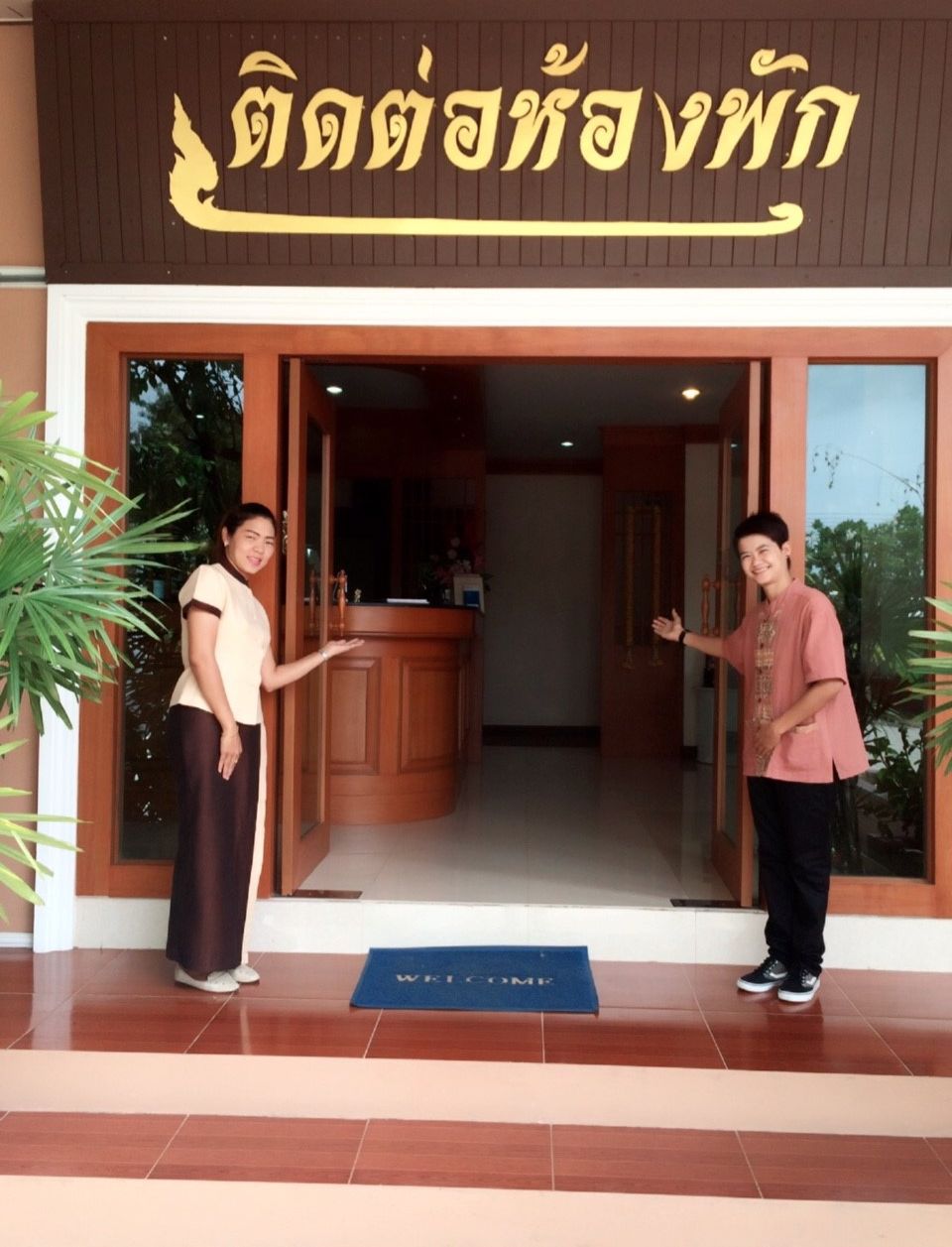 A hotel entrance with a reception desk and a welcome mat.