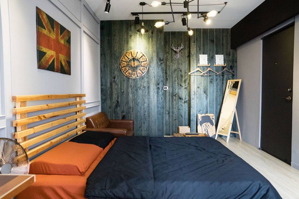 A modern bedroom with a wooden headboard, a large bed, a wall clock, and a wooden wardrobe.