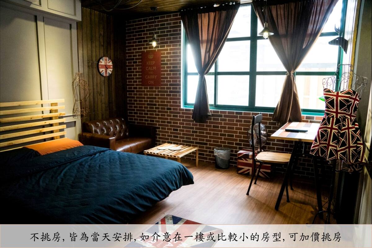 A cozy room with a bed, a small table, a chair, a window with curtains, and a wall clock.