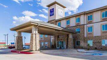 A hotel with a covered entrance, stone facade, and multiple windows.