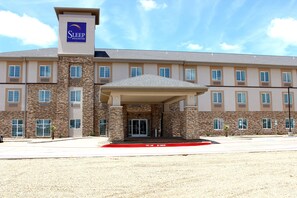 A Sleep Inn & Suites building with a stone facade, multiple windows, and a covered entrance. - Sleep Inn And Suites (Odessa)