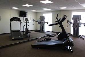 Un gimnasio con cinta de correr, elíptica y bicicleta estática.