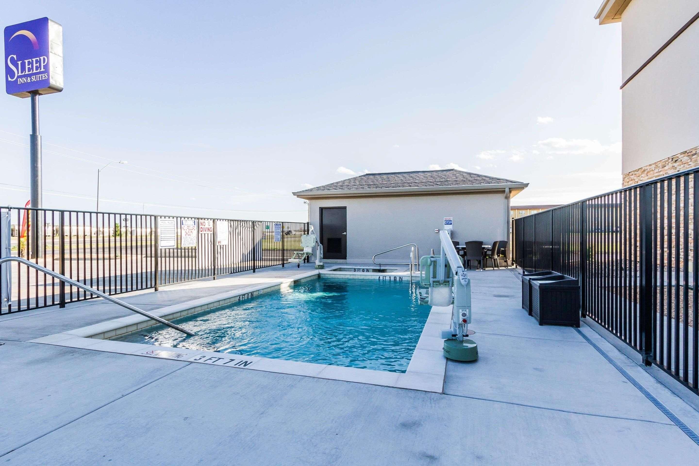 Ein Pool mit Zaun, ein Schild für Sleep Inn & Suites sowie ein Gebäude mit einer Tür.