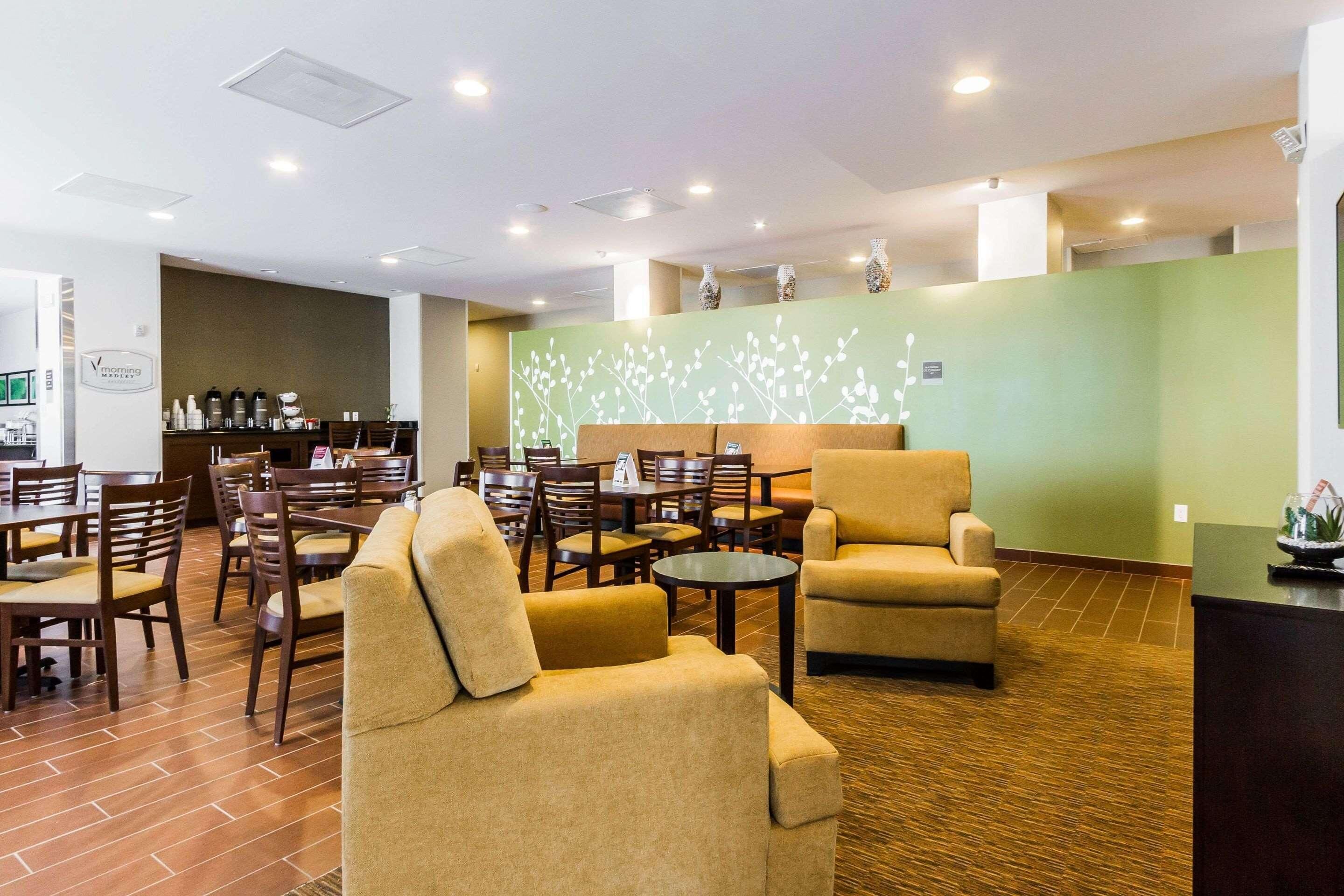 A hotel lobby with multiple seating areas, a reception desk, and a coffee station.