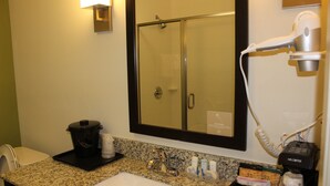 A bathroom with a sink, mirror, and a hairdryer on the counter. - Spark by Hilton Odessa (Odessa)