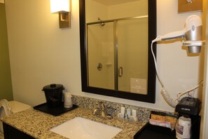 A bathroom with a sink, mirror, and a hairdryer on the counter. - Sleep Inn And Suites (Odessa)