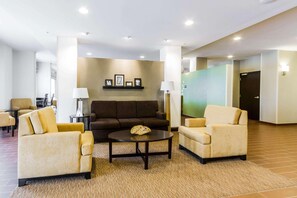 A hotel lobby with a sofa, armchairs, a coffee table, and a wall-mounted shelf with pictures. - Spark by Hilton Odessa (Odessa)