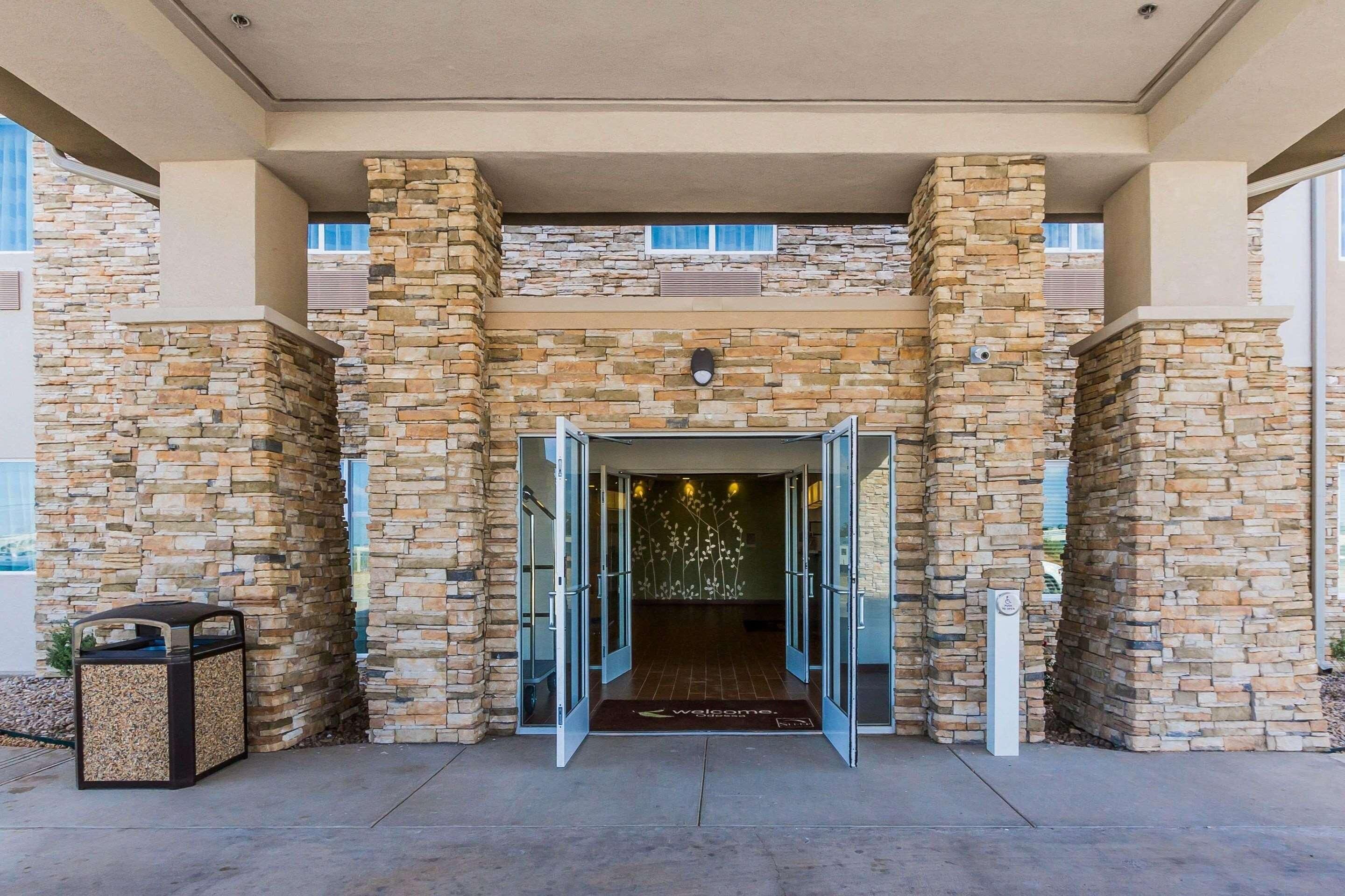 A building entrance with stone walls, a welcome mat, and a trash bin.