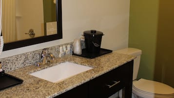 Un baño con lavamanos, espejo, toallero y retrete.
