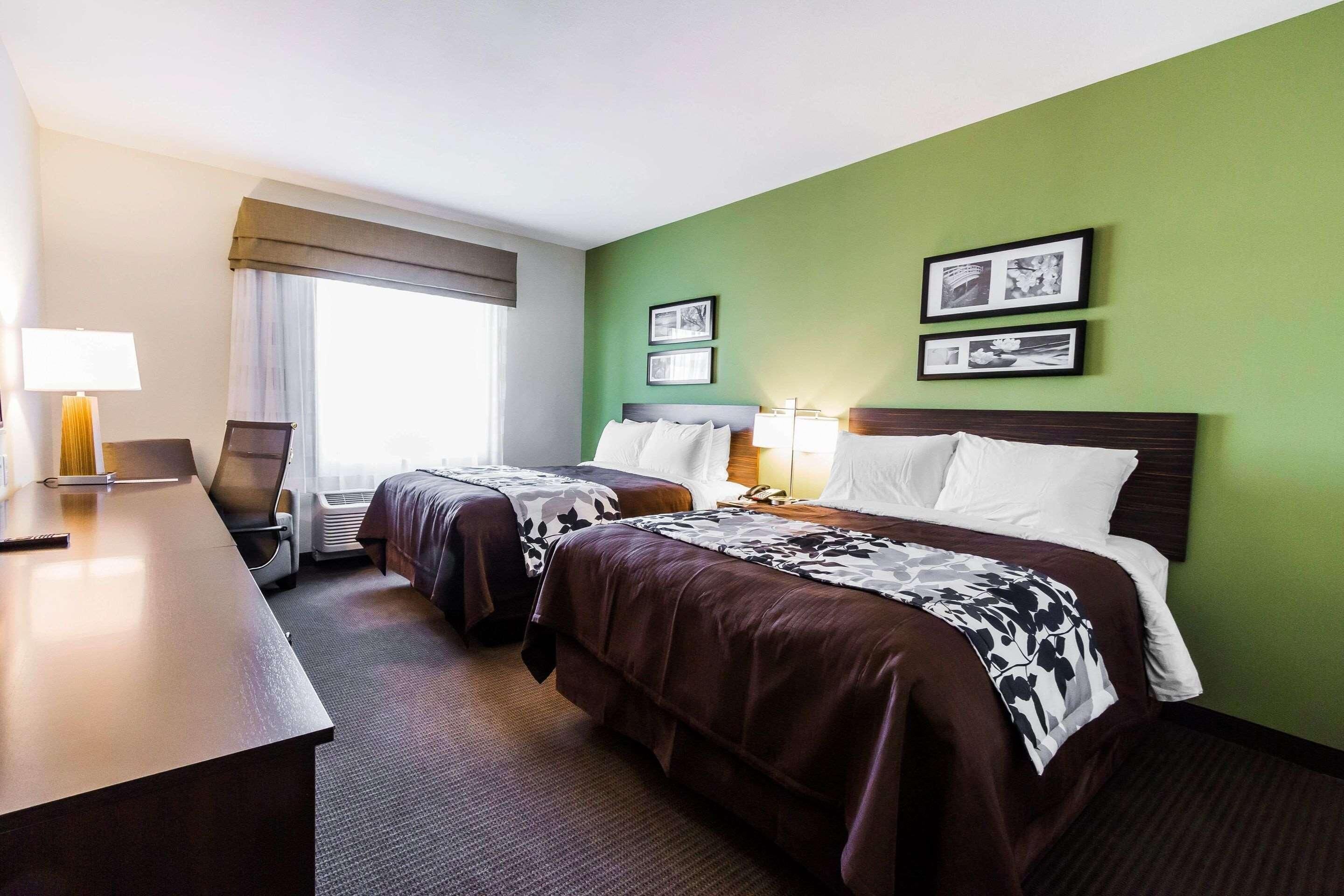 Een hotelkamer met twee bedden, een bureau, een stoel en een raam met gordijnen.