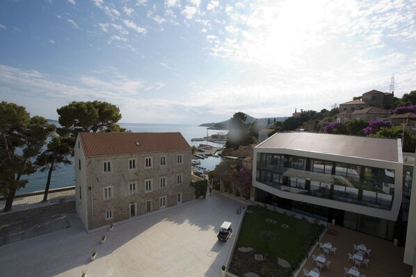Un edificio frente al mar con patio, vistas al océano y una estructura moderna con mesas al aire libre.