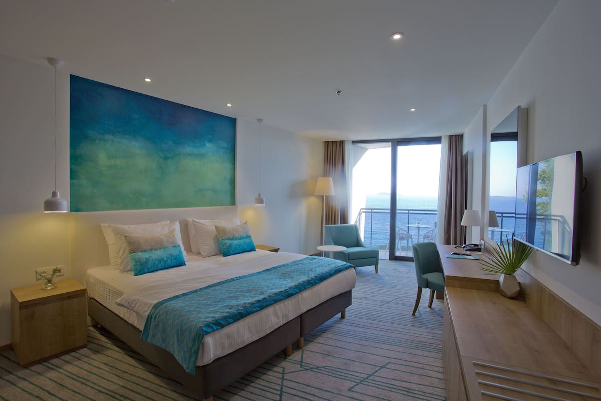 Ein modernes Hotelzimmer mit einem großen Bett, einem Schreibtisch und einem Balkon mit Aussicht.