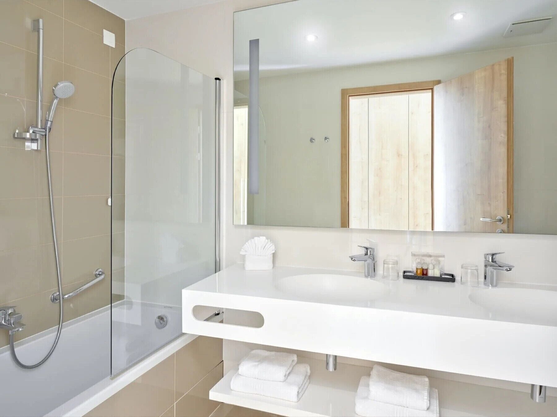 A modern bathroom with a glass shower enclosure, a large mirror, and a white vanity with a towel rack.